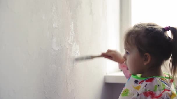 Repair, renovation, home, family, childhood, parenthood, fatherhood, self-isolation, quarantine concept - close-up little 3 years old girl playing with roller, paintbrush in apartment white paint. — Stock Video