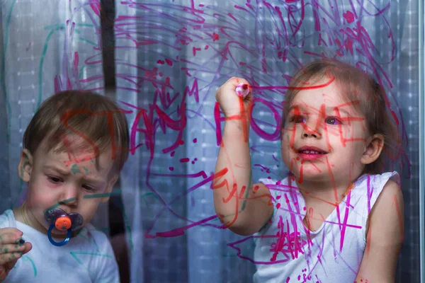 Kişisel izolasyon, ev karantinası, virüs, yalnızlık, can sıkıntısı, koruyucu maskeler, evde kalmak, güvende olmak, camlara resim yapmak, çocuk sanatı, duvar resimleri. Camda maske takan çocuk