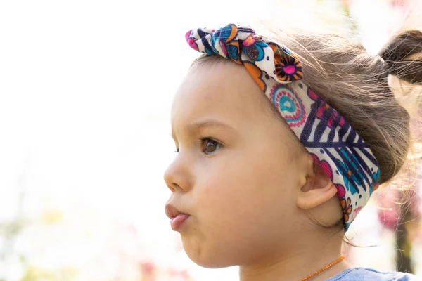 Vacker liten flicka med pannband på vårdagen i parken. Närbild — Stockfoto