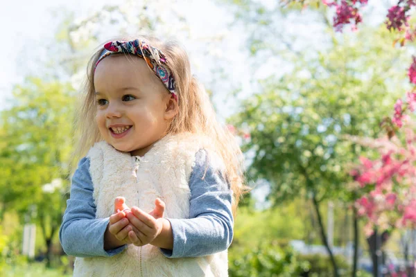 Tijd buiten doorbrengen. Oprechte emoties van een klein meisje. Mooi klein meisje met hoofdband in het voorjaar in het park. close-up uitzicht op kleine meisje dat is het houden van bloemen in haar handen — Stockfoto