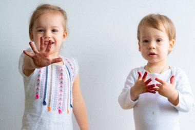 Resim çocuklar için eğlencelidir. Mutlu çocuklar kirli ellerle boyayla oynar. Erkek ve kız kardeş renkli resimde ellerle oynuyorlar. Çocuklar farklı duygular gösterir.