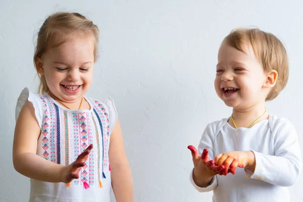 Festés szórakoztató a gyerekeknek - boldog gyerekek játszanak a festék piszkos kézzel. Testvérek játszanak a színes festményen. A gyerekek különböző érzelmeket mutatnak. — Stock Fotó