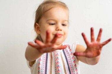 Resim çocuklar için eğlencelidir. Mutlu kız kirli ellerle oynar. Renkli resimde küçük kız ellerini gösteriyor. Küçük kız farklı duygular gösterir.