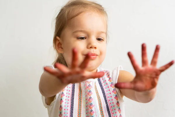 絵は子供にとって楽しいです-幸せな女の子は汚れた手で遊びます。赤ちゃんの女の子はカラフルな絵の中で彼女の手を示しています。女の子は違った感情を示しています — ストック写真