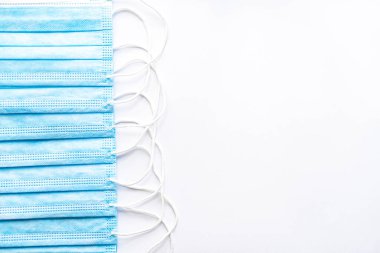 Beyaz arka planda tek kullanımlık yüz kalkanları üstüne birkaç tane tıbbi tek kullanımlık yüz kalkanı. Cerrahi pansuman ağız ve burnu kapatır. Sağlık, ilaç, covid-19, salgın konsepti..