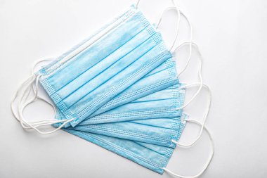 Birkaç tıbbi mavi kullan-at koruyucu maske üst üste beyaz arka planda vantilatör şeklinde. Cerrahi giysi ağız ve burnu kapatır. Sağlık, ilaç, covid-19, salgın konsepti..