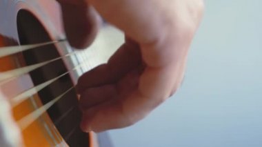 Müzik, yaratıcılık, konser, kendini izole etme konsepti. Akustik gitar radyosu çalan genç adamın yakın çekim elleri. Parmaklar dizgileri fretboard akorlarına basarak ayır.