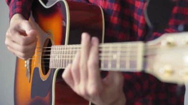 Müzik, yaratıcılık, konser, kendini izole etme konsepti. Akustik gitar radyosu çalan genç adamın yakın çekim elleri. Parmaklar dizgileri fretboard akorlarına basarak ayır.