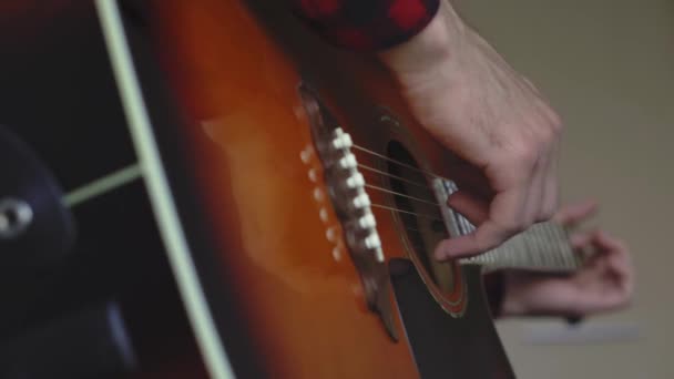 Music, creativity, concert, self-isolation concept. Close-up hands of young man playing an acoustic guitar dreadnought in soft focus. Fingers sort out strings by pressing chords on frets of fretboard. — Stock Video