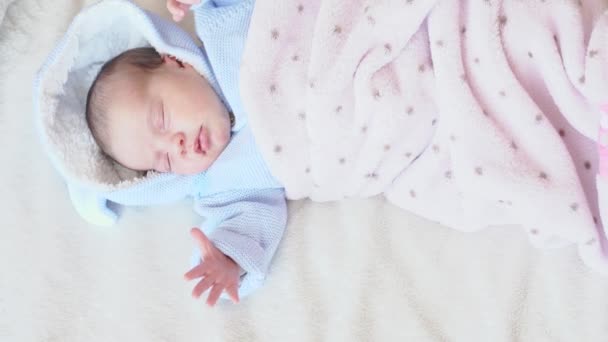 유아, 유아, 부모, 어머니, 가족 개념 - 파란 블라우스를 입은 채 수평으로 누워 있고 하얀 배경에 핑크 담요로 덮여 있는 한 갓난아기 가잠자고 있는 모습. — 비디오