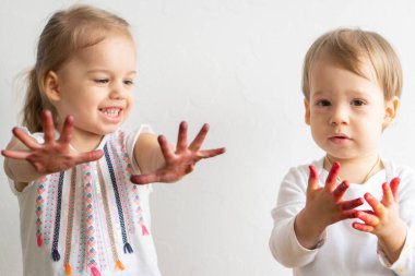 Resim çocuklar için eğlencelidir. Mutlu çocuklar kirli ellerle boyayla oynar. Erkek ve kız kardeş renkli resimde ellerle oynuyorlar. Çocuklar farklı duygular gösterir.