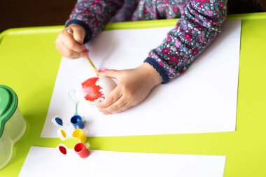 Mutlu Paskalyalar. Küçük kız ressam yumurta boyadı. Çocuk Paskalya için hazırlanıyor. Boyalı el. Parmak boyası. Sanat ve zanaat konsepti. Geleneksel bahar bayramı yemeği. Çocuklar boyayla resim yapar.