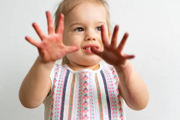 Schilderen is leuk voor kinderen - gelukkig meisje speelt t met vuile handen. Meisje toont haar handen in het kleurrijke schilderij. Klein meisje toont verschillende emoties — Stockfoto