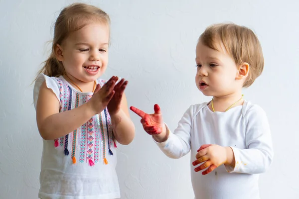 Schilderen is leuk voor kinderen - gelukkige kinderen spelen met de verf met vuile handen. Broer en zus spelen met handen in het kleurrijke schilderij. Kinderen vertonen verschillende emoties — Stockfoto