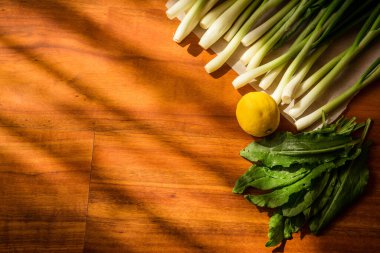 Kahverengi arka planda yeşiller. Frenk soğanı, kuş, limon.