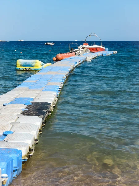 Temporary marina for boats and moored boats in the Red Sea. Long pier leaving in the blue sea