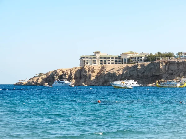 Güzel bir denizin kayalık sahilinde beyaz bir otel. Mısır 'da dinlenme, kaya, gemi, temiz su