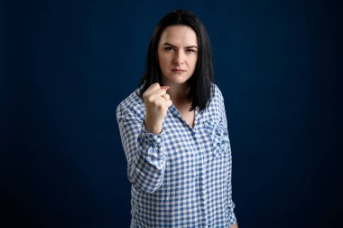 Sıradan giyinmiş genç bir kadın yumruğunu gösteriyor.