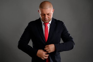 Havalı iş adamının portresi siyah takımını gri arka planda izole eder.