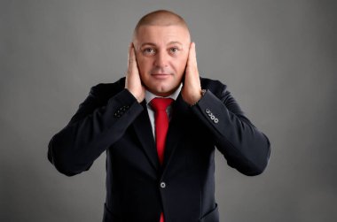 Duymadıkları üç bilge iş adamı, zarif siyah takım elbise ve gri arka planda izole edilmiş kırmızı kravat takıyor.