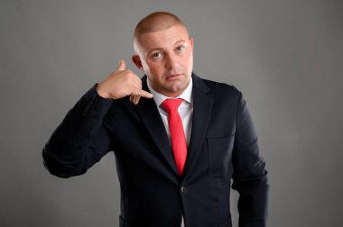 Zarif siyah takım elbiseli havalı iş adamının portresi ve gri arka planda 