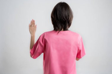 Pembe hastane kıyafetleri giymiş, kahverengi saçlı, beyaz, izole edilmiş arka planda poz veren genç kadın hemşire ya da doktor..