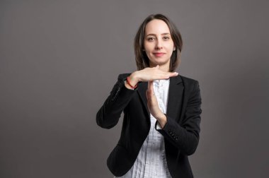 Siyah takım elbiseli ve gömlekli harika bir iş kadını portresi. İzole edilmiş gri arka planda jest pozu veriyor.