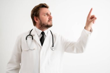 Tıbbi üniformalı steteskoplu erkek doktorun portresi, beyaz izole bir arkaplanda duran sanal bir düğmeye basıyor.