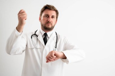 Üzerinde steteskop olan erkek doktorun portresi zamanın beyaz bir arka planda poz verdiğini gösteriyor.