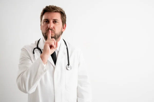 男性医師の肖像とともに聴診器で医療制服ショーシージェスチャーポージング上の白い隔離された背景 — ストック写真