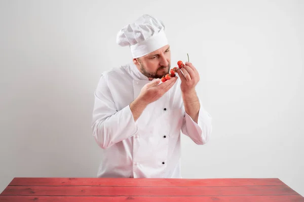 Jovem Chef Masculino Branco Uniforme Cheiro Tomate Posando Fundo Branco — Fotografia de Stock