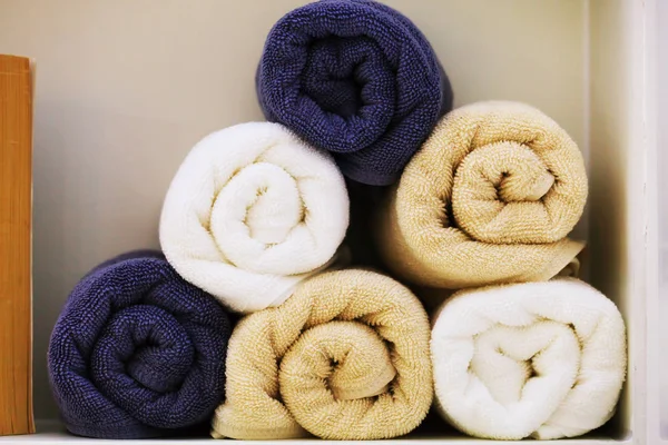 Bunch of earth tone towels in bathroom shelf — Stock Photo, Image