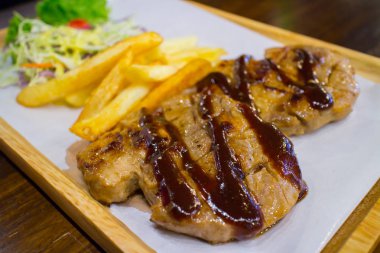 Patates kızartması ve salata ahşap plaka üzerinde ızgara domuz