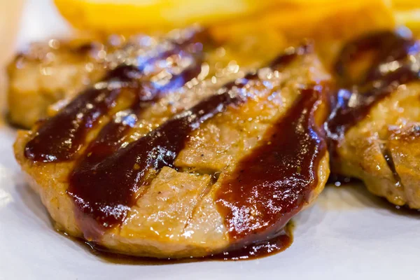 Cerdo a la parrilla con papas fritas y ensalada en plato de madera — Foto de Stock