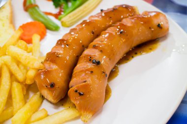 Beyaz tabakta Frech Fried ile soslu ızgara sosis