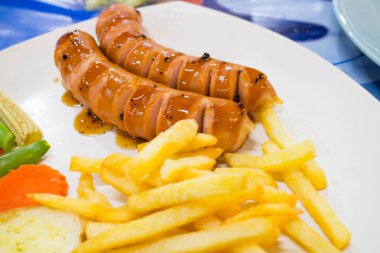 Beyaz tabakta Frech Fried ile soslu ızgara sosis