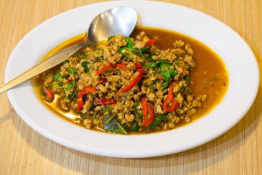 Beyaz tabakta domuz kıyması ve fesleğenle kızartılmış. (Ka Prao Moo)