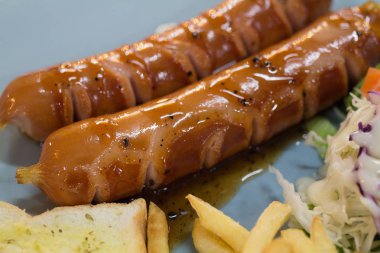 Izgara sosis sosu ve taze salata ve patates kızartması ile