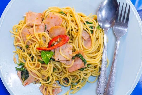 fusion food, spaghetti with fried crispy bacon ,sausage and basil leave, hot and spicy food, international cuisine