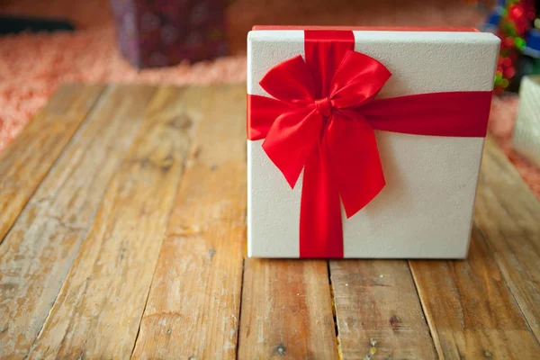 Witte geschenkdoos en rood lint op hout achtergrond met ruimte — Stockfoto