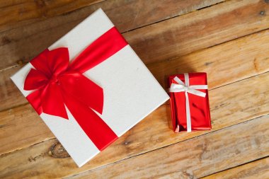 Beyaz hediye kutusu ve alan ahşap zemin üzerine kırmızı kurdele