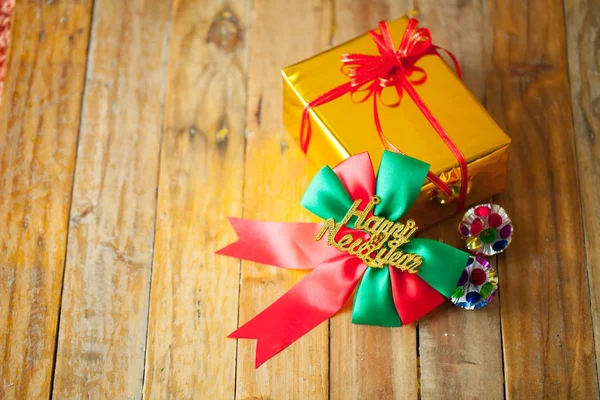 Scatola regalo d'oro e nastro rosso e felice anno nuovo regalo su legno b — Foto Stock