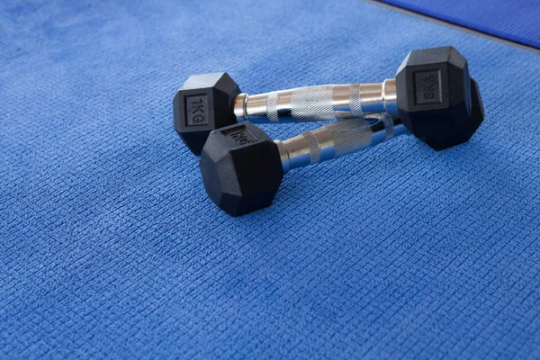 Sports dumbbells on yoga blue material background. Weight Traini