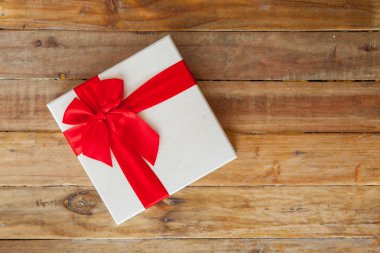 Beyaz hediye kutusu ve kırmızı kurdele ve geri ahşap üzerine mini kalp içinde