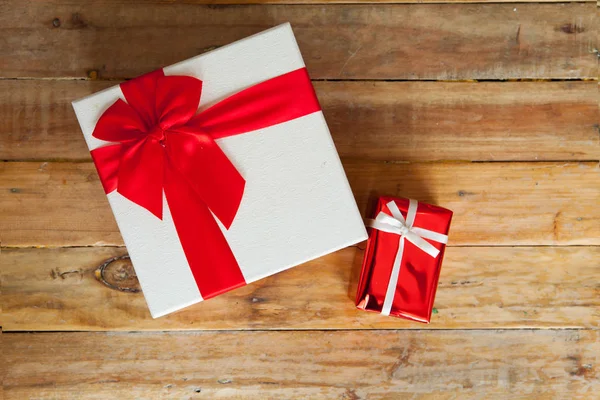 Witte geschenkdoos en rood lint op hout achtergrond met ruimte — Stockfoto