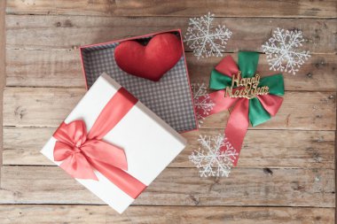 Beyaz hediye kutusu ve kırmızı kurdele ve geri ahşap üzerine mini kalp içinde