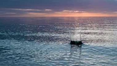 Taş ağır çekimde suya düşer. Su, güzel günbatımında sıçrar..