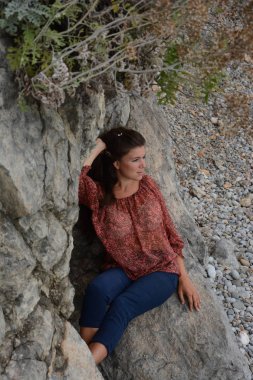 Kayalıklarda bir dizi fotoğraf. Mutlu bir kadın tatil boyunca sahilde dinleniyor ve keyif alıyor açık denizde ya da doğa denizinde tatil yapıyor.