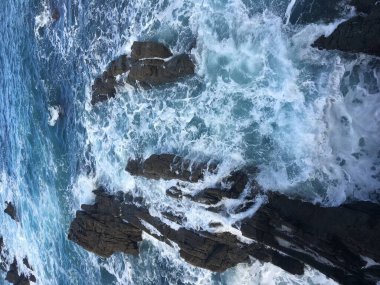 İspanya 'nın Asturias kentindeki güzel bir sahil köyü olan Cudillero' daki Cantabrian Denizi 'nde kayalara vuran dalgalar