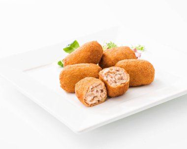 Beyaz arka planda kare seramik tabağa yerleştirilmiş bir avuç lezzetli kesilmiş kroket.